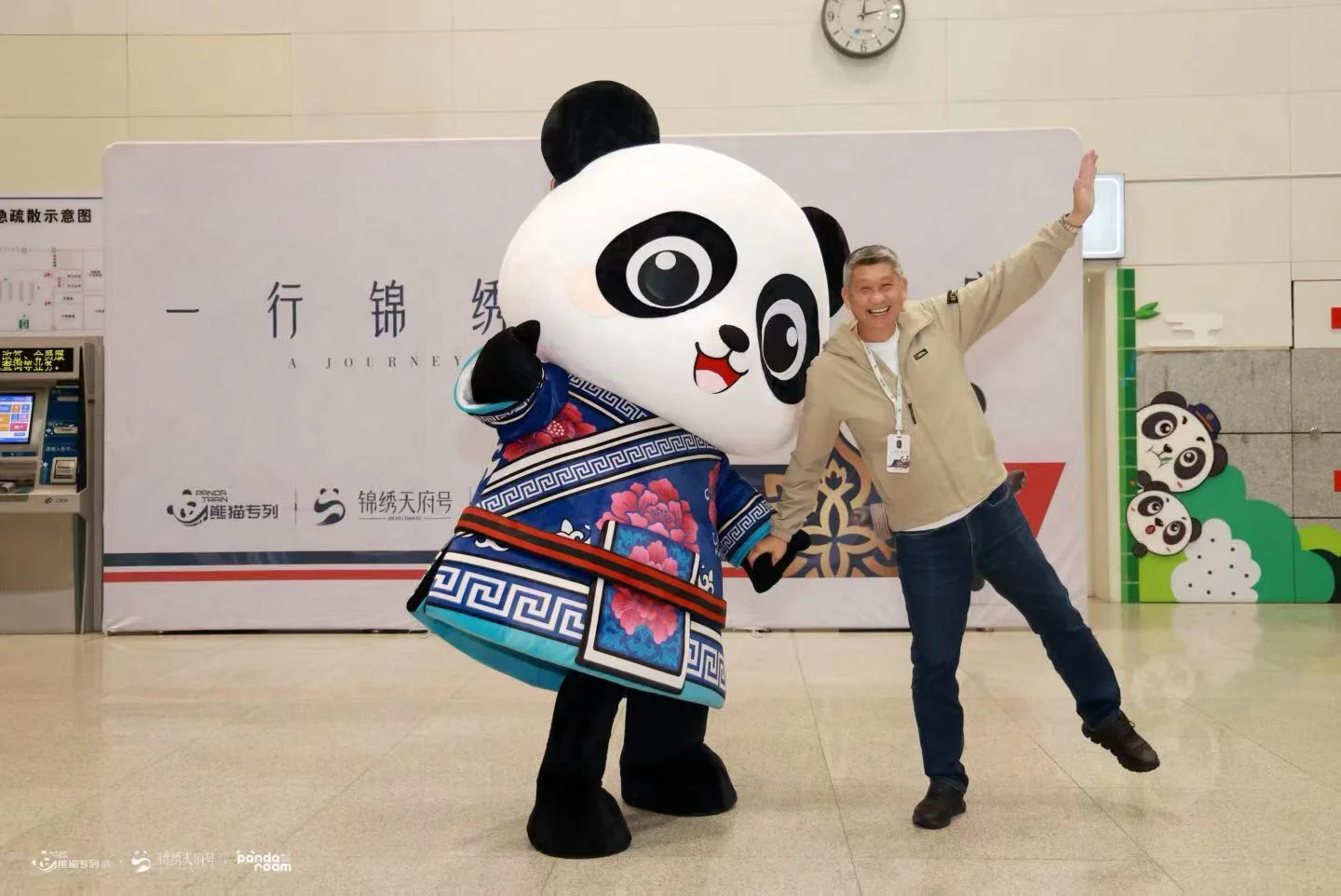 A guest with a panda welcome character beside Jinxiu Tianfu branding