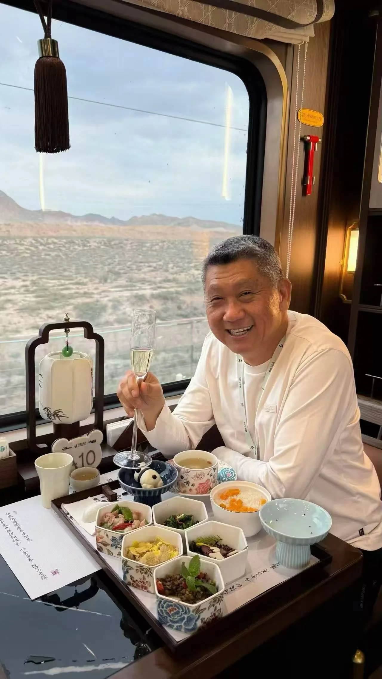 A guest beside a window dining table on Jinxiu Tianfu, with individually served dishes and tea utensils on the table