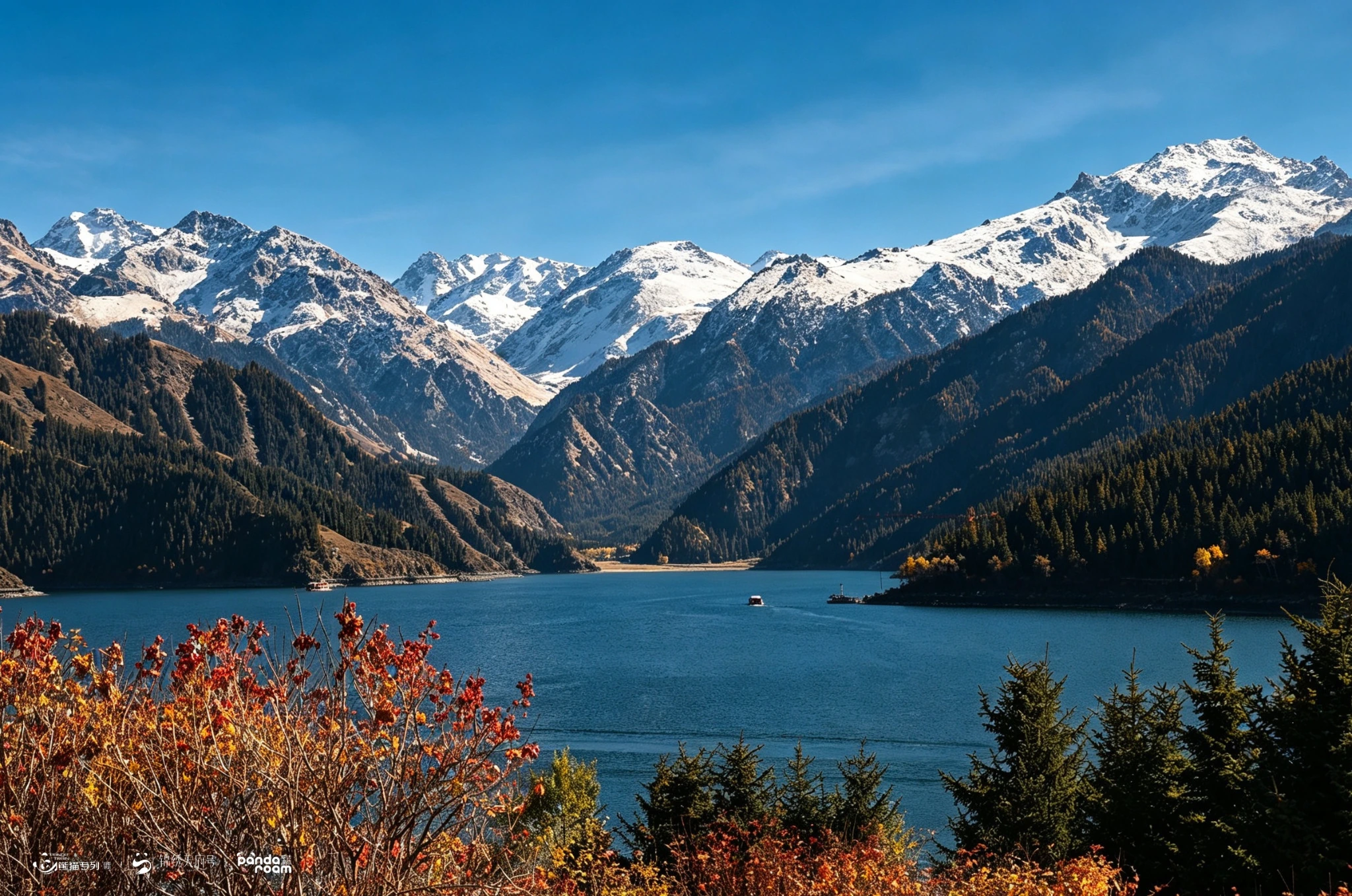 Blue lake below dark slopes and distant snow-covered mountains in Xinjiang